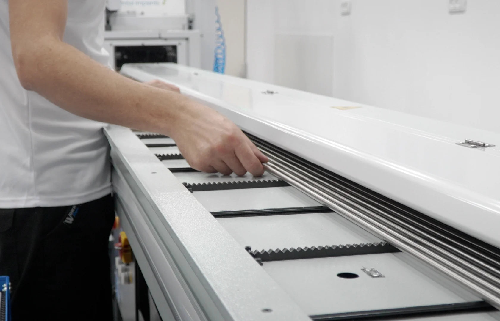 Production worker placing Titanium Grade 5 rods into a machining system for dental implant manufacturing.