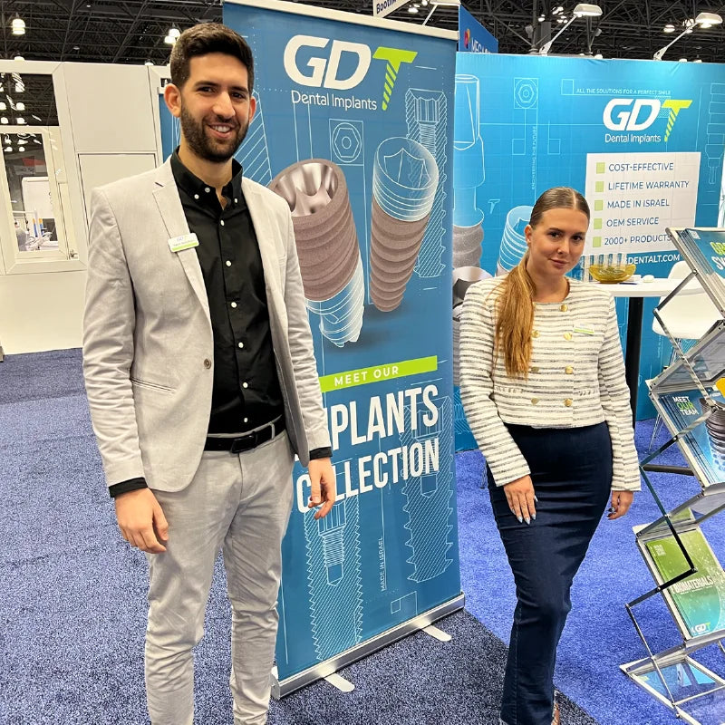 GDT Dental Implants representatives holding branded signs at the IDS 2023 booth in Cologne, Germany.