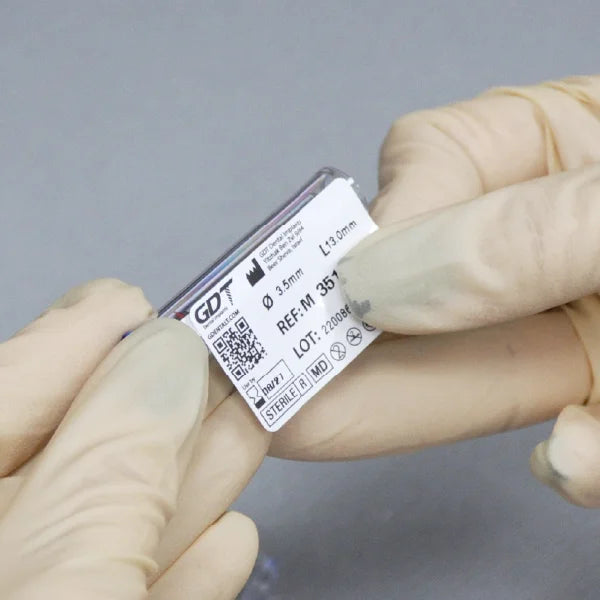 Gloved hands presenting the GDT MOR Internal Hex implant identification sticker with product specifications and traceability details.