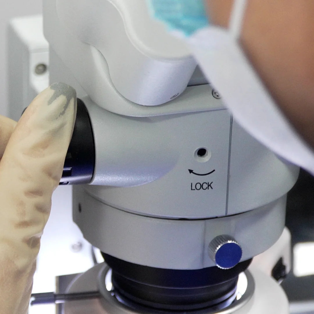 Close-up inspection of dental implant components under a laboratory microscope.